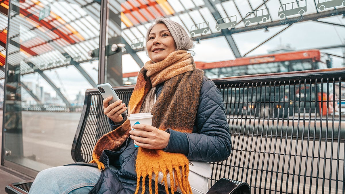 Woman at a train station looking at her phone while using an experiential microlearning tool